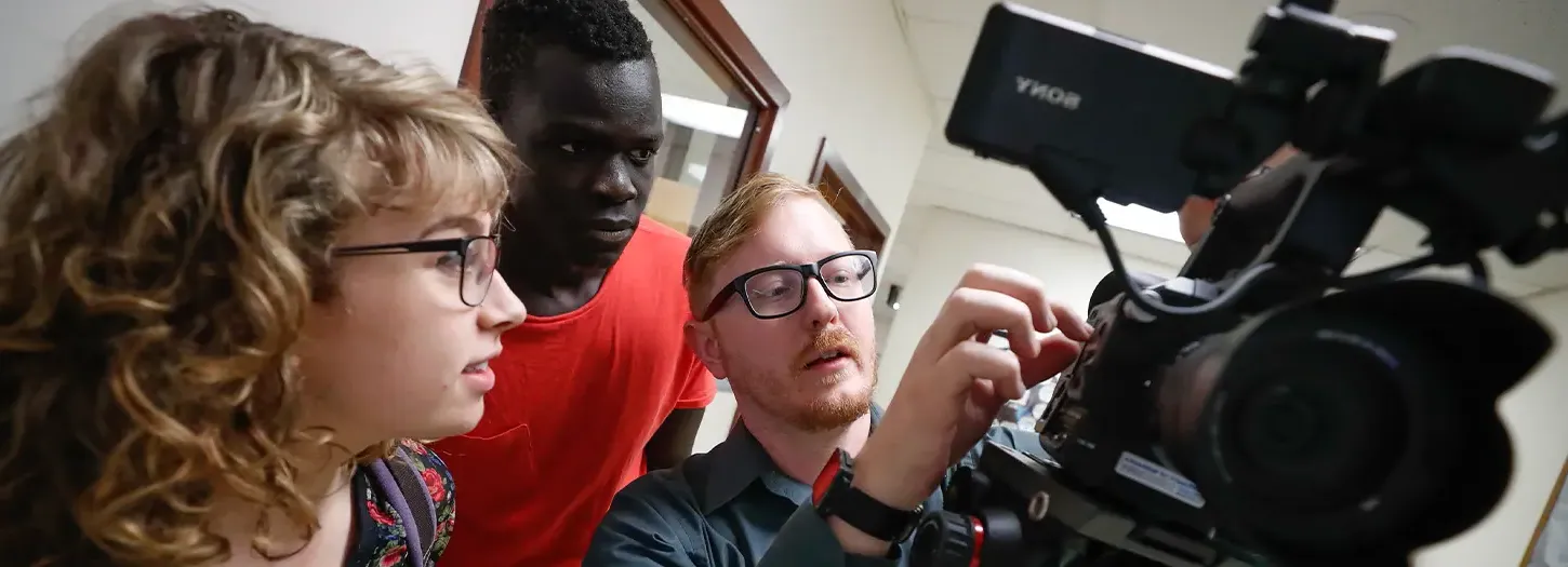 Student working with a video camera with a professor