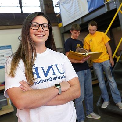 a students poses in an Industrial Distribution lab