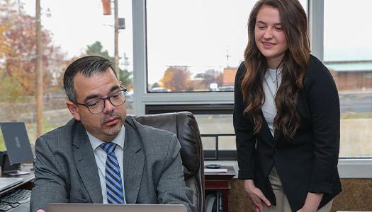 image of a teacher showing information to a student on a laptop