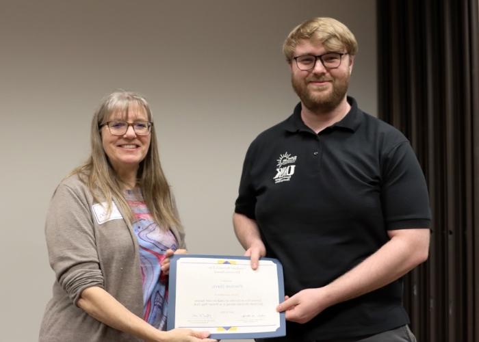 Woman presenting man with award.