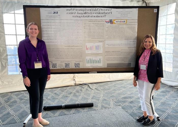 Two women standing in front of a research poster.