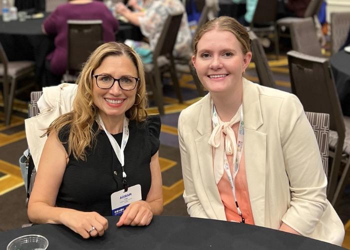 Two women sitting at a table smiling at the camera.