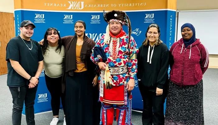 students from the FNSA group pose with a speaker in traditional native american dress